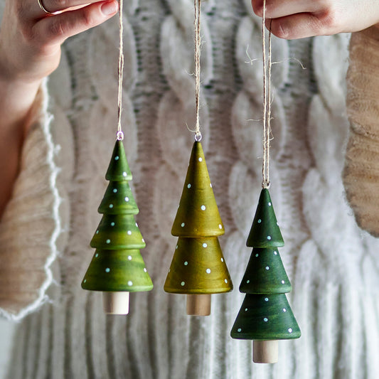 Nahaufnahme der gebeizten Holzstruktur und handbemalten weißen Punkte der Tannenbaum-Anhänger aus Gummibaumholz.