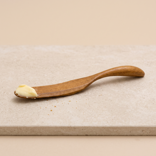 Nahaufnahme der natürlichen Holzmaserung und geschwungenen Form des Teak-Buttermessers.