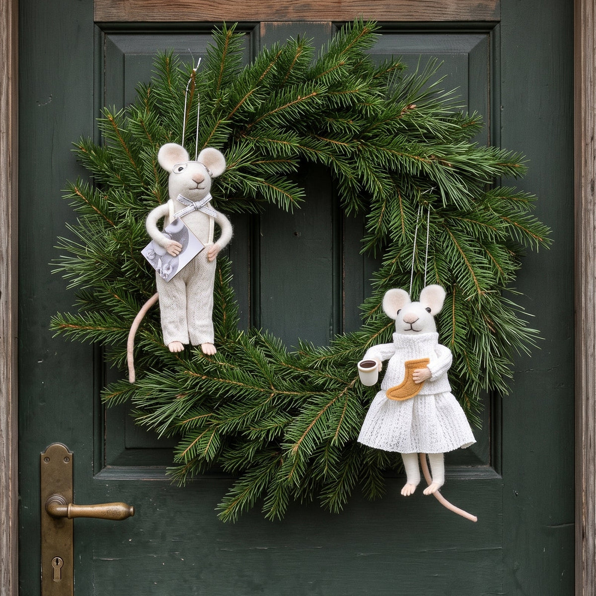 Die weihnachlichen Aufhänger in Mäuseform aufgehängt an einem Zweig au Tannenzweigen an einer dunkelgrünen Haustüre.