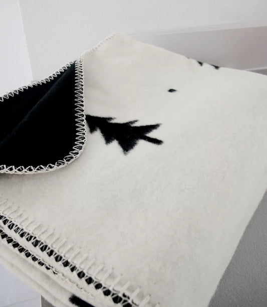 Detailaufnahme der Kuscheldecke Smilla mit weicher Bio-Baumwoll-Webstruktur und kontrastierendem Tannenbaum-Wendemuster.