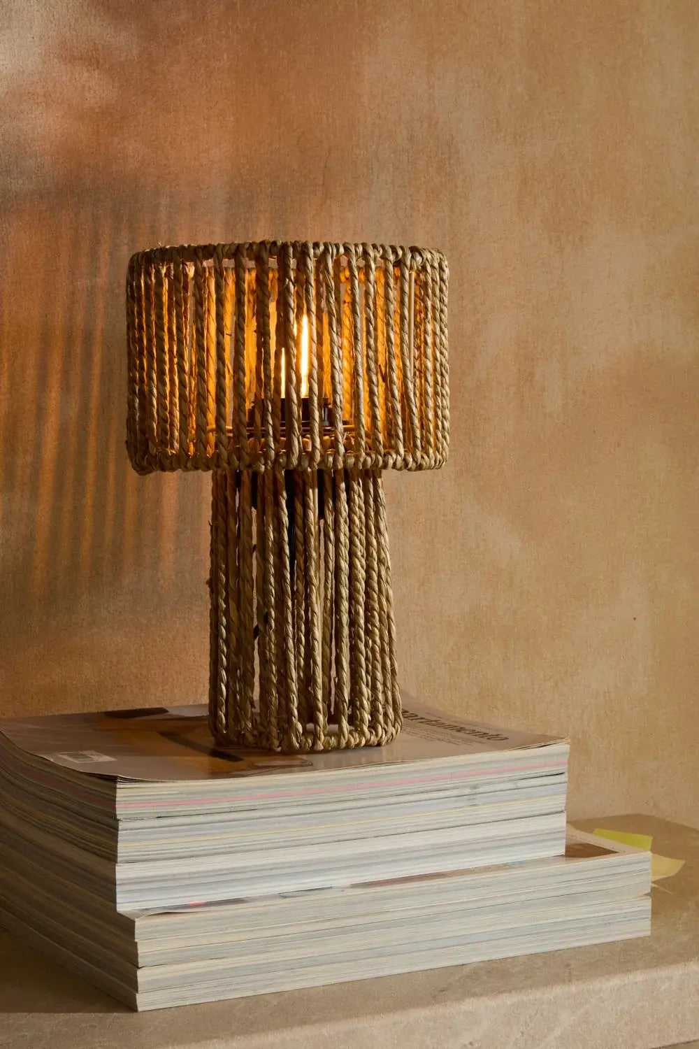 Die gemütliche Tischlampe Nuri mit warmem Lichtschein auf einer Kommode im Wohnzimmer.