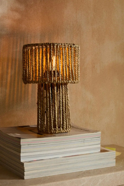 Die gemütliche Tischlampe Nuri mit warmem Lichtschein auf einer Kommode im Wohnzimmer.