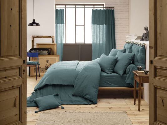 Die blaue Kuscheldecke als dekorativer Überwurf auf einem hölzernen Tagesbett.