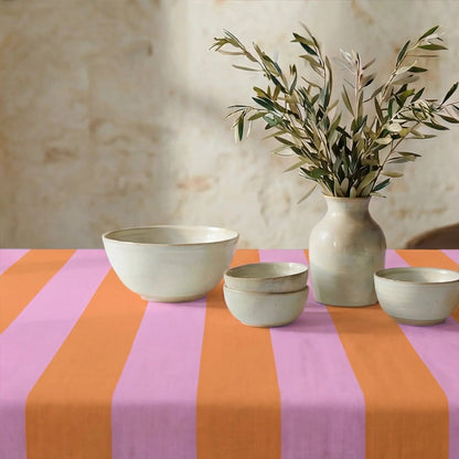 Die sommerlich gestreifte Tischdecke einladend gedeckt mit heller Keramik und einer Vase mit Olivenzweigen.