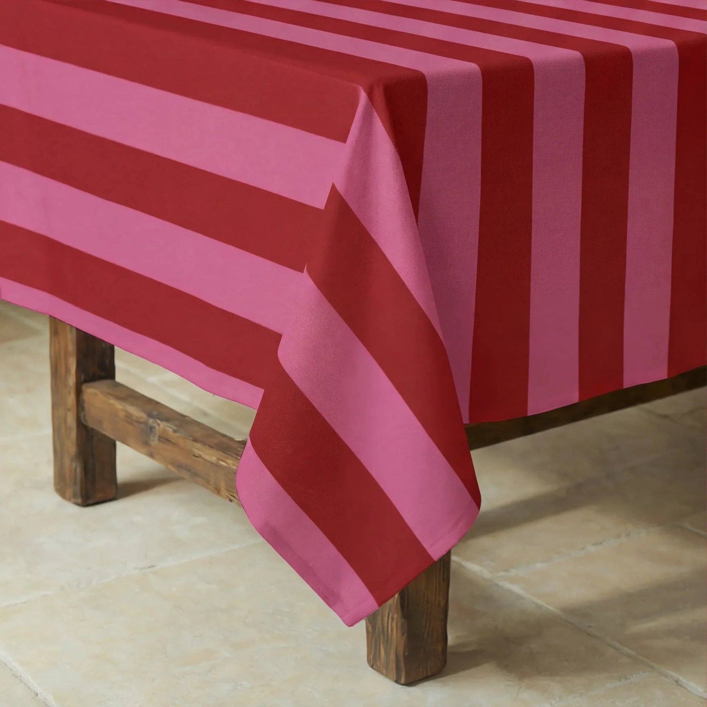 Nahaufnahme der rosa-roten Streifen der Tischdecke auf einem dunklen Holztisch.