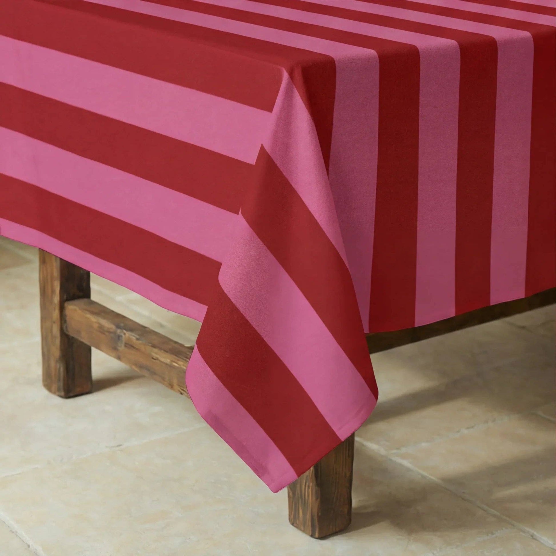 Nahaufnahme der rosa-roten Streifen der Tischdecke auf einem dunklen Holztisch.