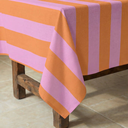 Nahaufnahme der rosa-orangen Streifen der Tischdecke auf einem dunklen Holztisch.