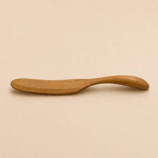 Buttermesser aus Teakholz in der Gesamtansicht vor hellem Hintergrund.