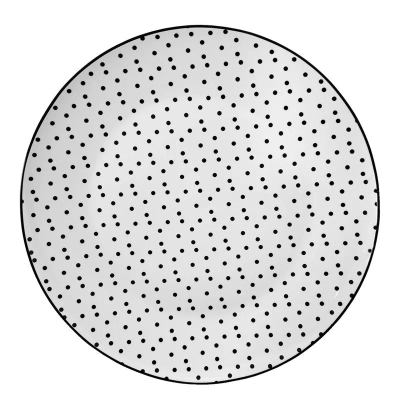 Weißer Porzellanteller mit vielen kleinen schwarzen Punkten (Ø 26 cm) in der Gesamtansicht vor hellem Hintergrund.