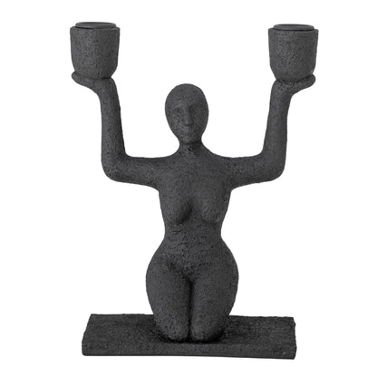 Kerzenhalter Lucie sitzende Frau in Schwarz in der Gesamtansicht vor hellem Hintergrund.