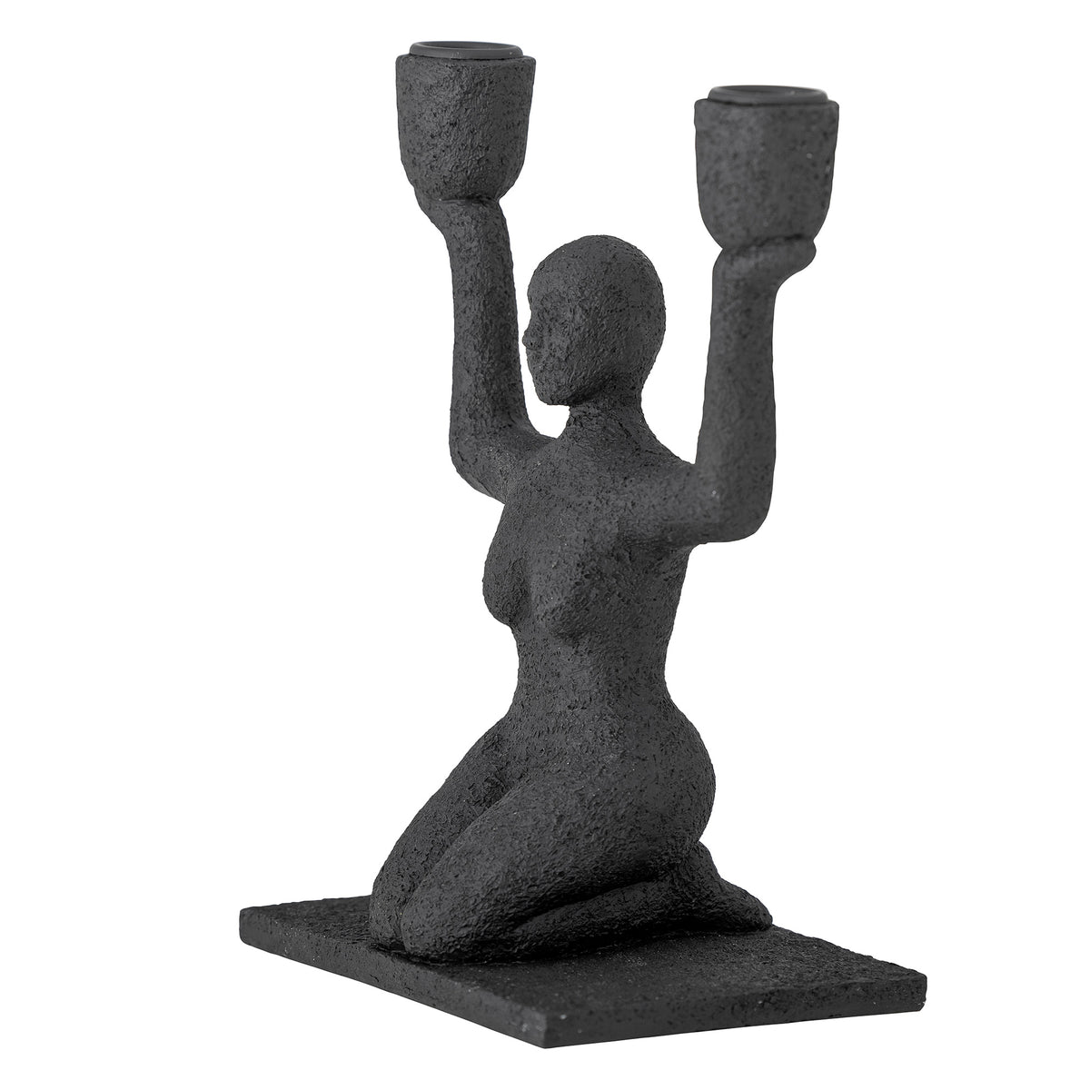 Kerzenhalter Lucie sitzende Frau in Schwarz in der seitlichen Ansicht vor hellem Hintergrund.