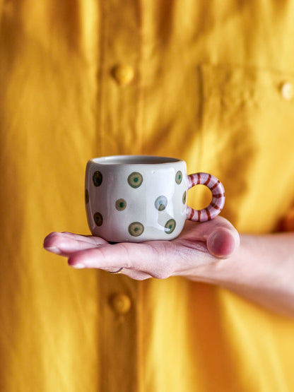 Nahaufnahme des gestreiften Henkels und der fröhlich grünen Punkte auf der Steingut-Tasse.