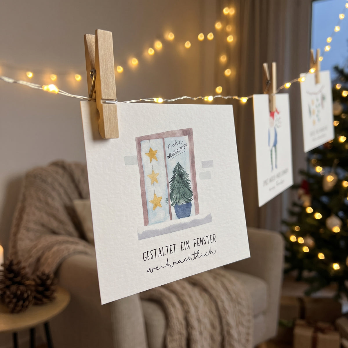 Ein Kärtchen-Adventskalender mit je einer Aufgabe für die ganze Familie, um gemeinsame Zeit zu verbringen, hängt an einer Lichterkette im Wohnzimmer, das weihnachtlich dekoriert ist.