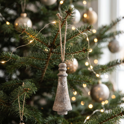 Silberner Weihnachtsanhänger aus Holzwerkstoff (6x16 cm) aufgehängt an einem geschmückten Tannenbaum.