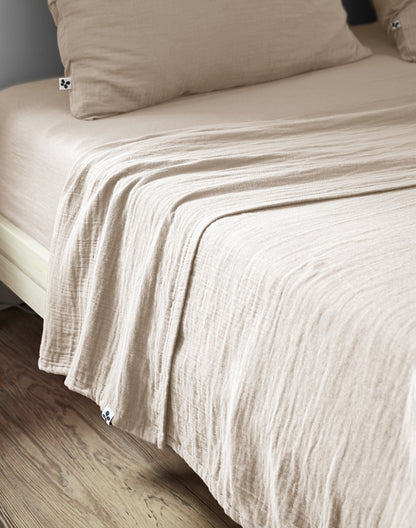 Riesige XXL-Musselin-Überwurfdecke Pampa aus Baumwollgaze in Beige-Creme auf einem Doppelbett.