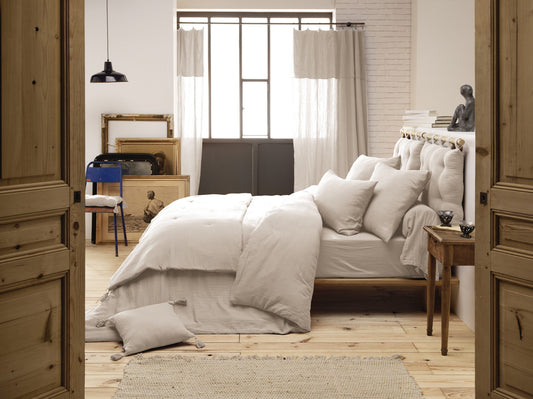 Die beige Kuscheldecke als dekorativer Überwurf auf einem hölzernen Tagesbett.