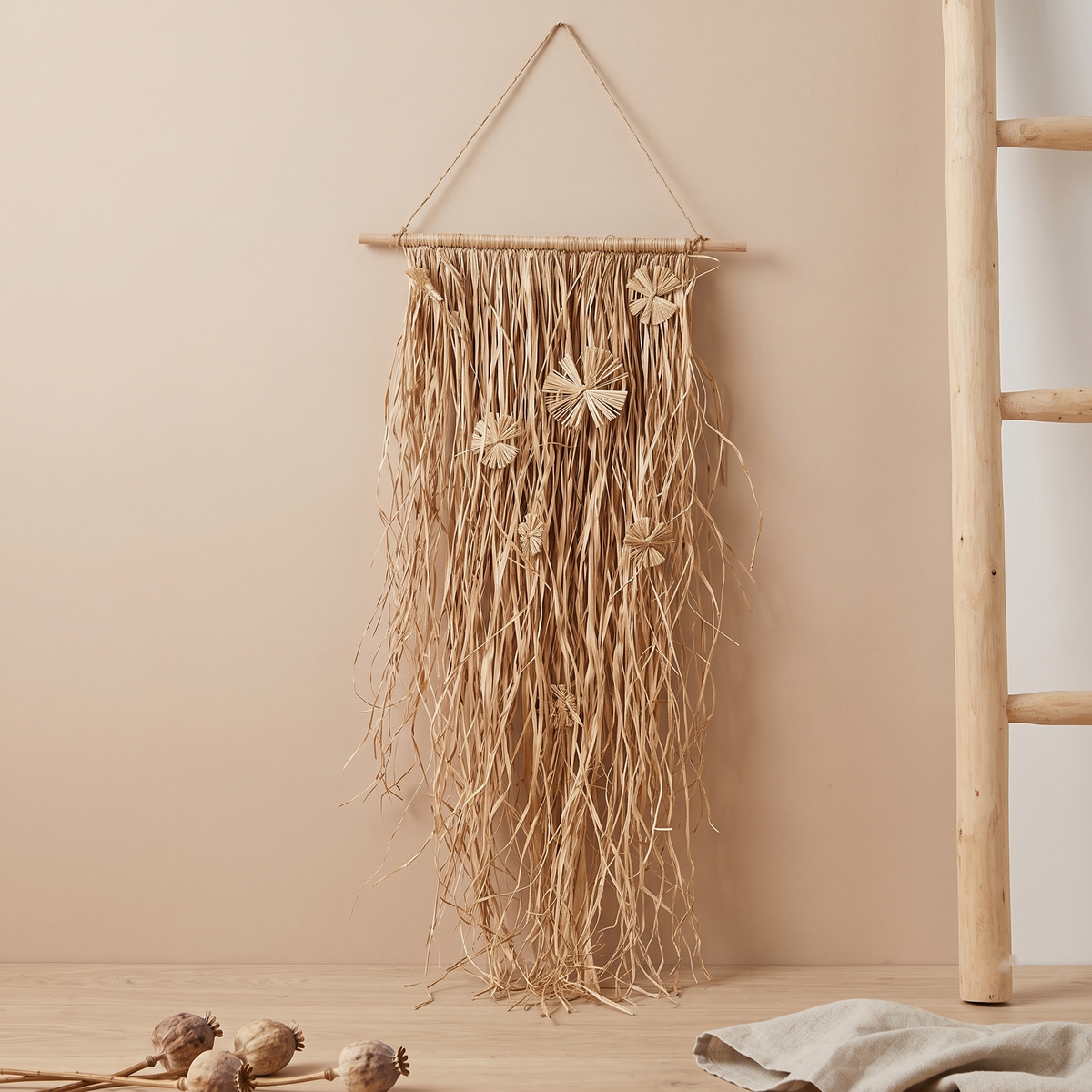 Das große Deko-Palmblatt als stilvoller, natürlicher Wandschmuck neben einer Holzleiter.