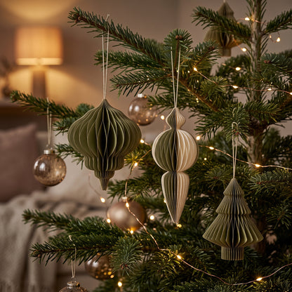 Die grünen Ornamente aus Papier hängen an den Zweigen eines Christbaums im Wohnzimmer, der mit einer Lichterkette geschmückt ist. 