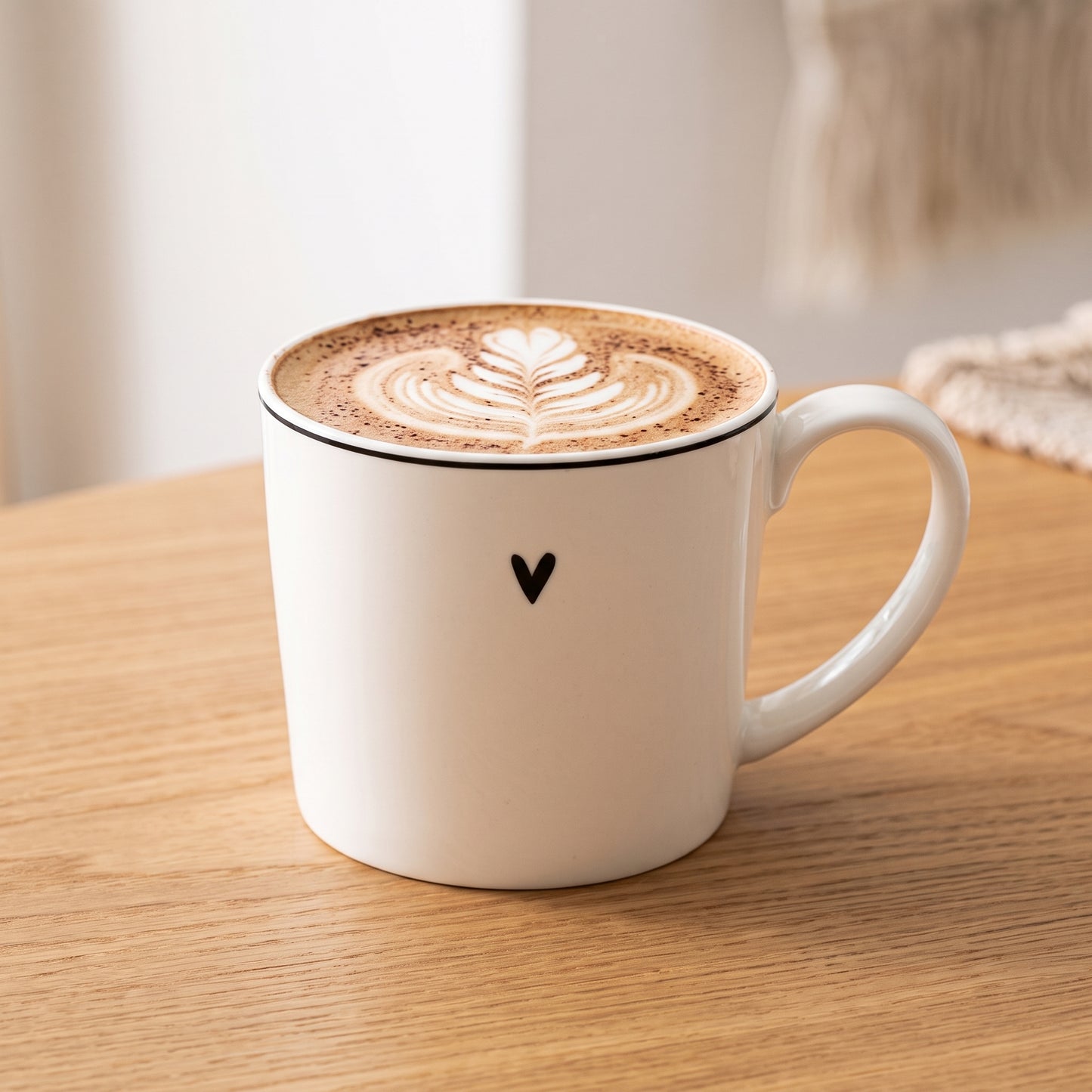 Weiße Tasse mit Herzmotiv gefüllt mit Cappuccino auf einem Holztisch.