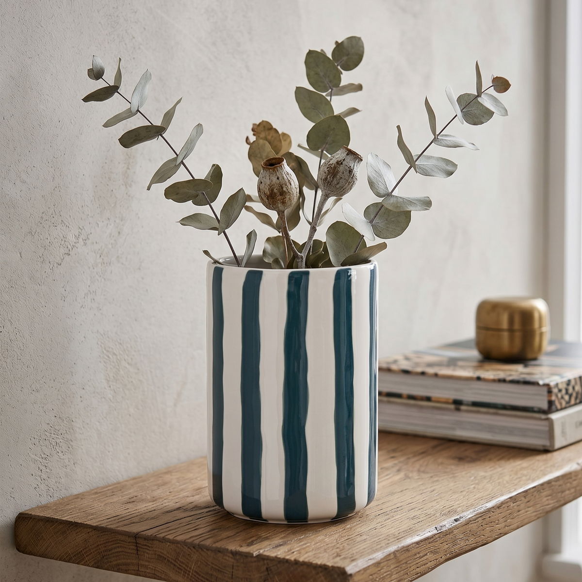Die minimalistische gestreifte Keramikvase mit getrockneten Zweigen als stilvoller und frischer Blickfang im Wohnbereich