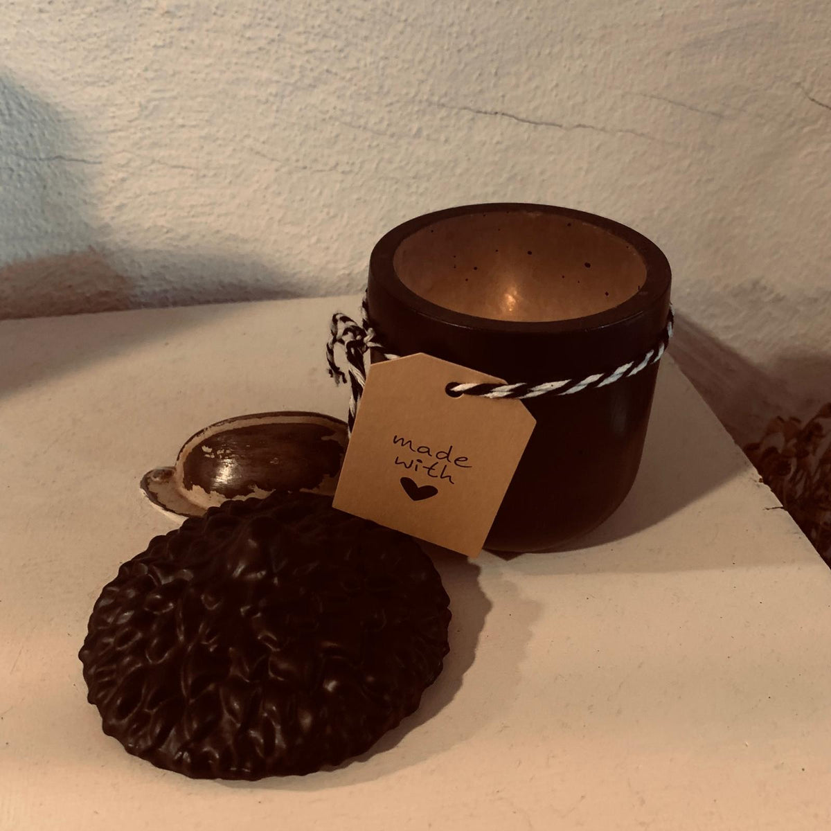 Schwarze Deko-Eichelschale aus Stewalin stilvoll arrangiert auf einem hellen Holztisch mit einer brennenden Kerze.