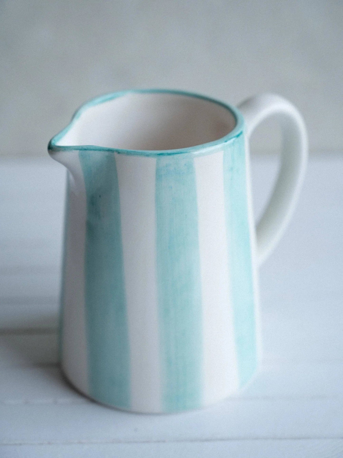 Nahaufnahme des Steingut-Milchkrugs mit Fokus auf den handbemalten blauen Streifen und der feinen Keramik-Textur.