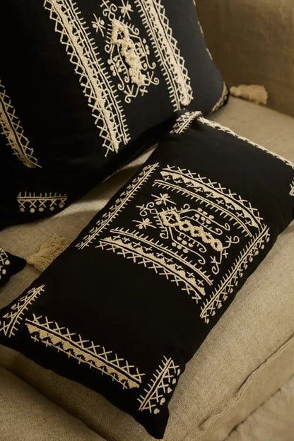 Der bestickte Boho-Kissenbezug Traste dekorativ arrangiert auf einer hellen Couch.