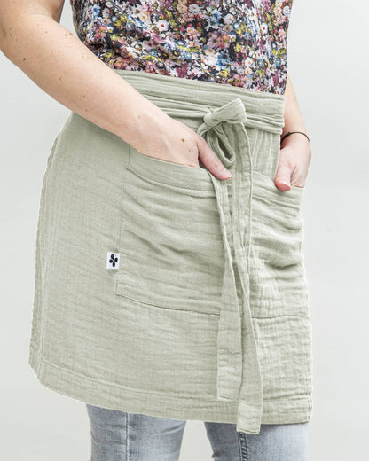 Salbeigrüne Gartenschürze aus 100% Baumwoll-Gaze mit Taschen und langen Bändern zur Schnürung.