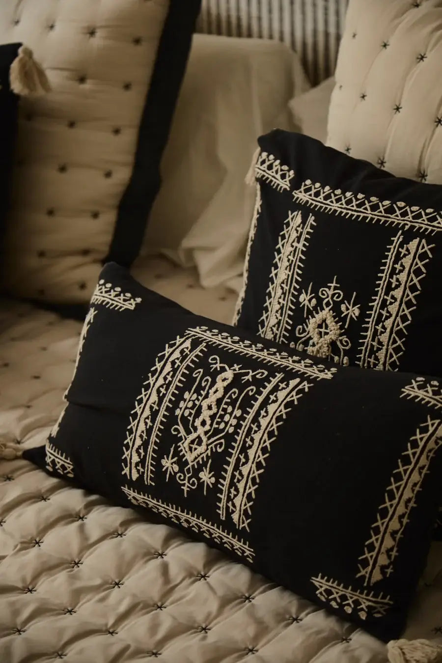 Der bestickte Boho-Kissenbezug Traste dekorativ arrangiert auf einem hellen Bett im Schlafzimmer.