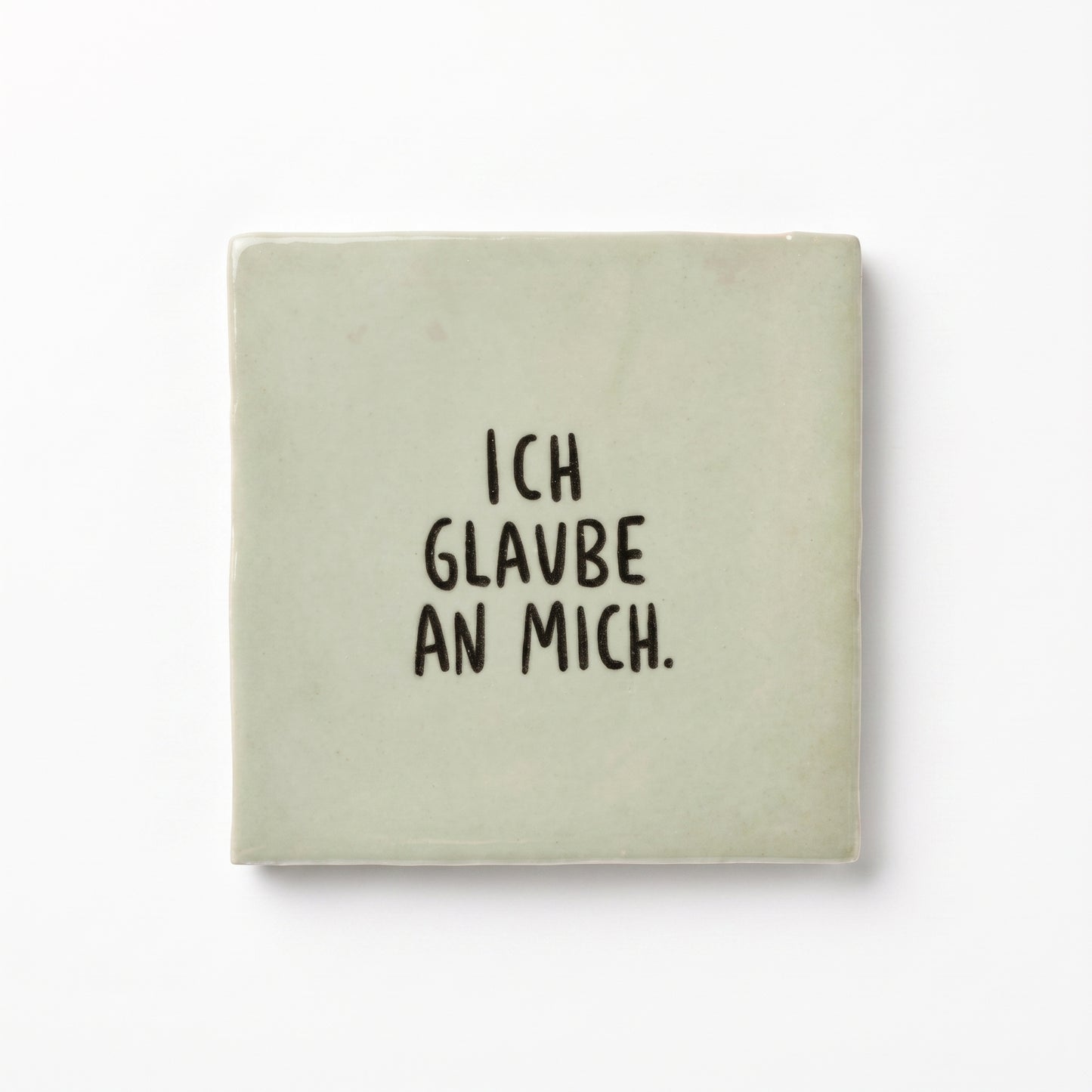 Hellgrüne Dekokachel mit schwarzer Aufschrift Ich glaube an mich in der Gesamtansicht auf weißem Hintergrund.
