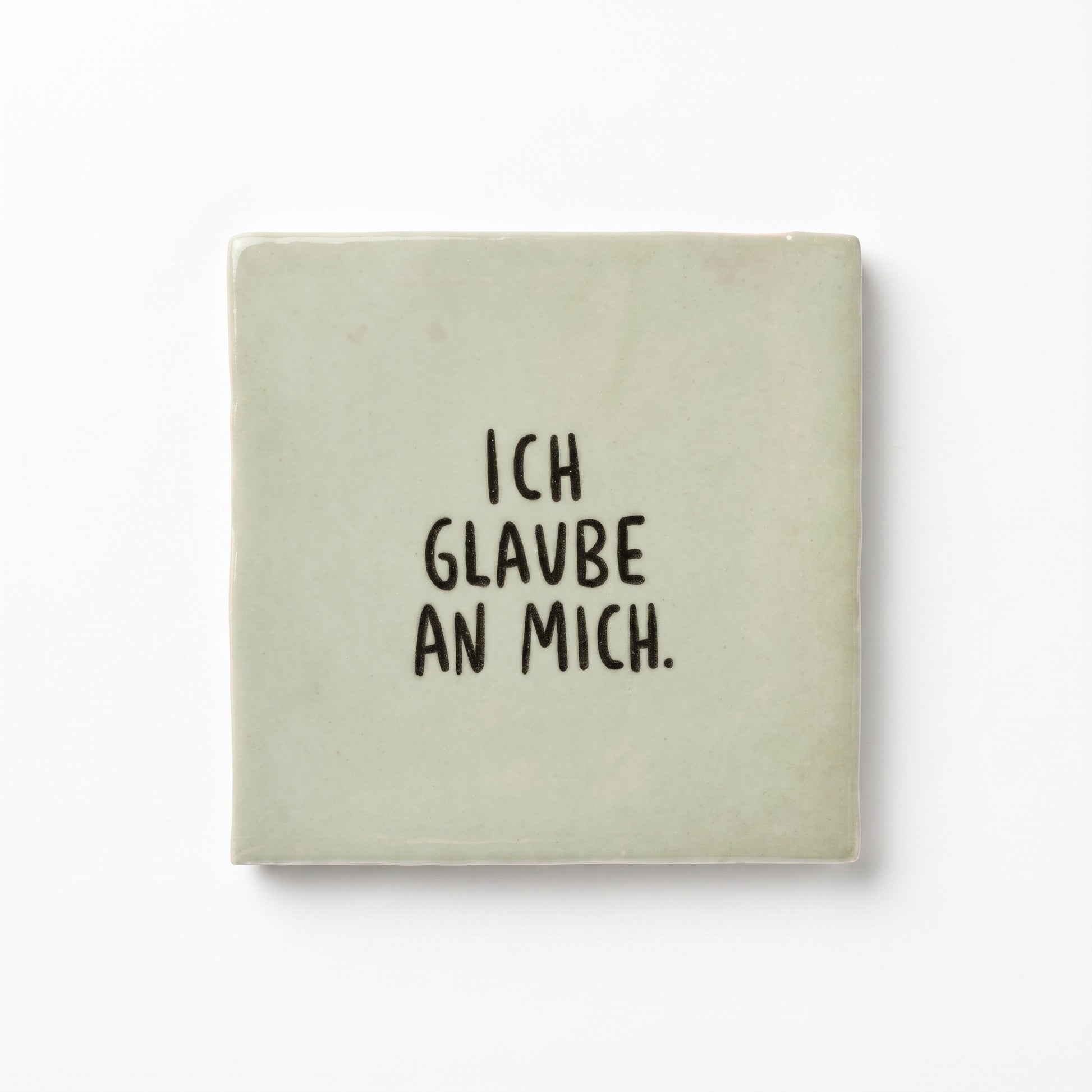 Hellgrüne Dekokachel mit schwarzer Aufschrift Ich glaube an mich in der Gesamtansicht auf weißem Hintergrund.