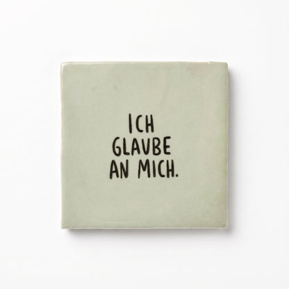 Hellgrüne Dekokachel mit schwarzer Aufschrift Ich glaube an mich in der Gesamtansicht auf weißem Hintergrund.