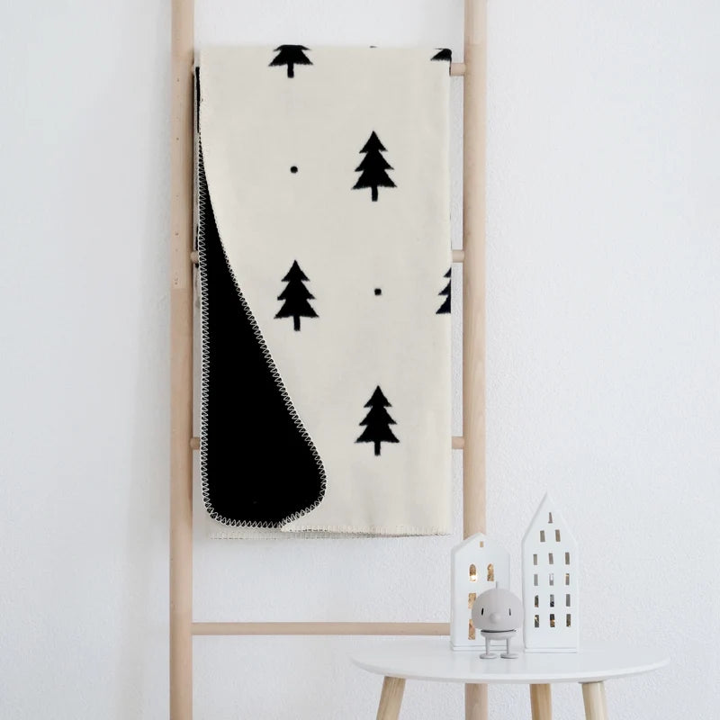 Kuscheldecke Smilla (150x200 cm) drapiert auf einer hellen Holzleiter.