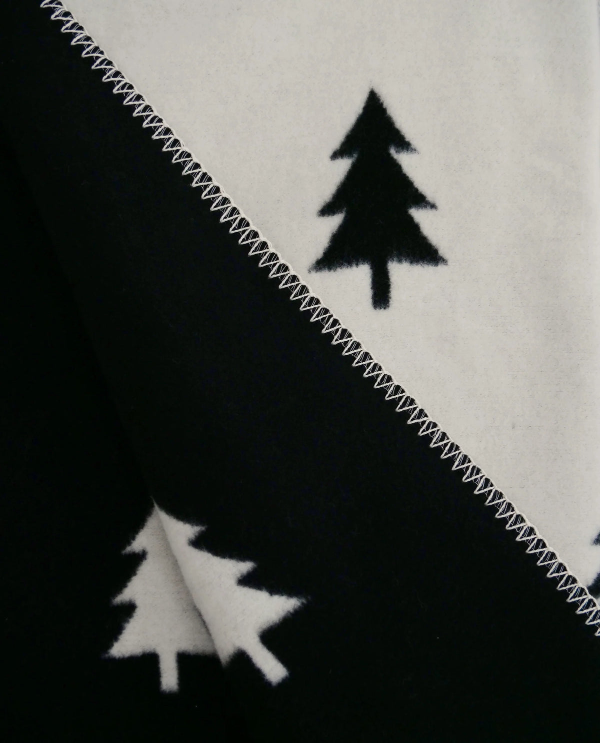 Detailaufnahme der Kuscheldecke Smilla mit kontrastierendem Tannenbaum-Wendemuster.